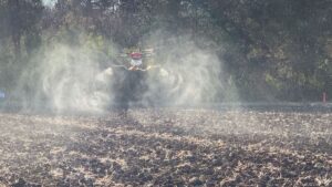 農地上空で農薬散布を行う産業用ドローンの飛行風景（低空飛行による散布作業）